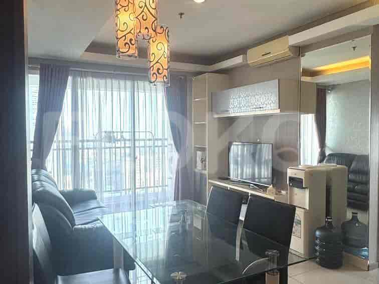 Modern living room with black sofa, glass dining table, and large windows.