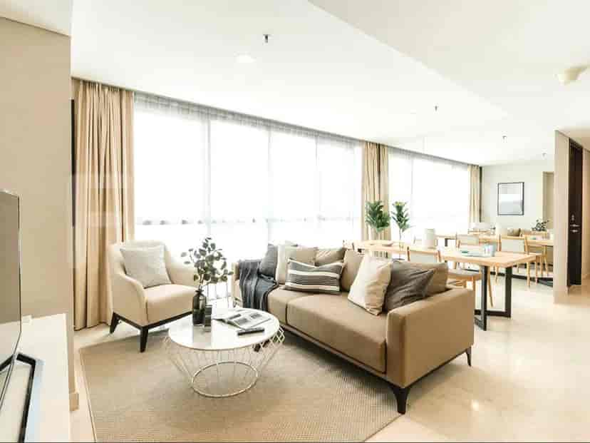 Living room with a sofa, armchair, coffee table, and dining area with large windows.