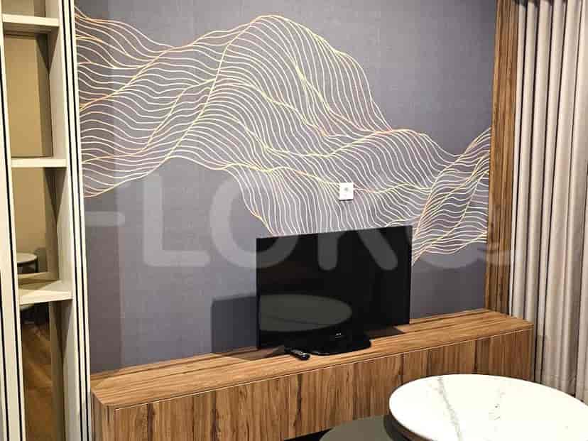 Living area with a TV mounted on a wooden cabinet, decorative wall art, and a round table.