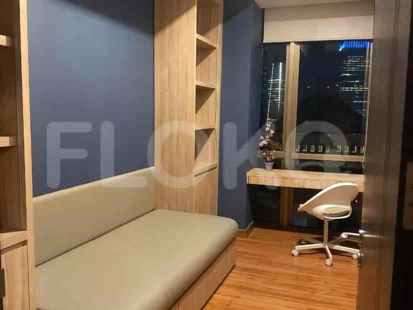 A bedroom with a sofa, desk, and shelving unit, bathed in soft blue light.