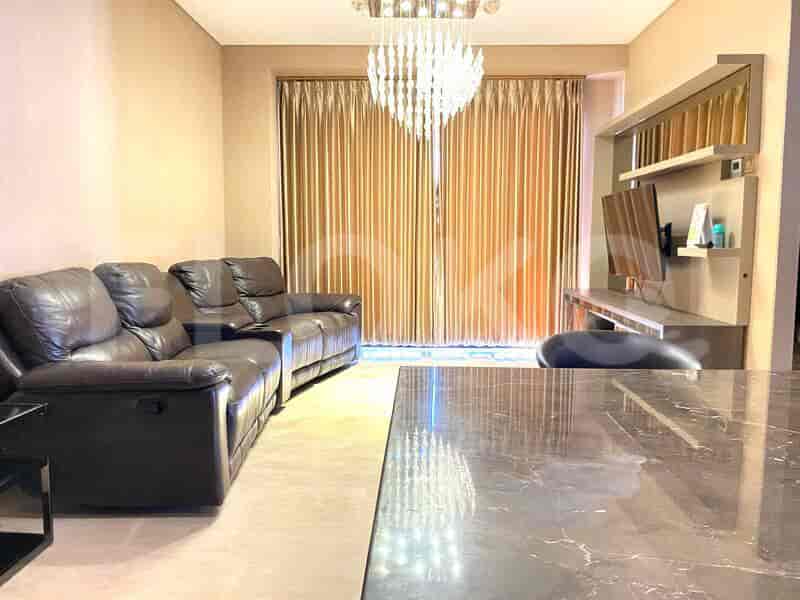 A modern living room featuring a leather sofa, a chandelier, and a television with a dark marble table.
