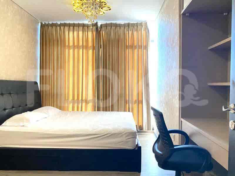 A bedroom with a bed, a study table, and windows with curtains.