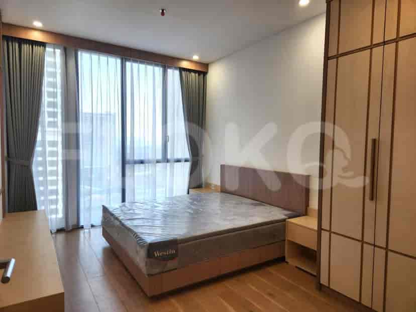 Kamar tidur yang terang benderang dengan tempat tidur besar, jendela besar, dan lemari.