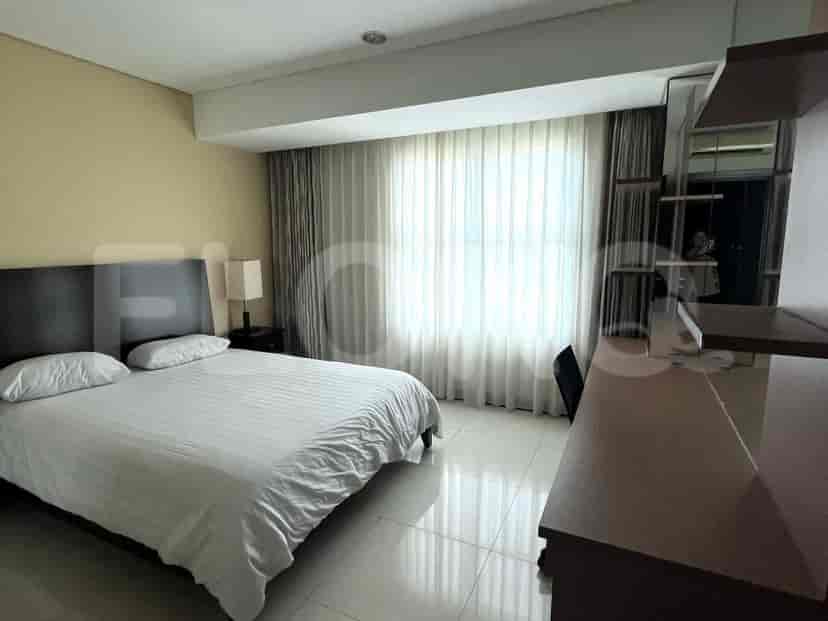 A bedroom with a bed, bedside table, and large window.
