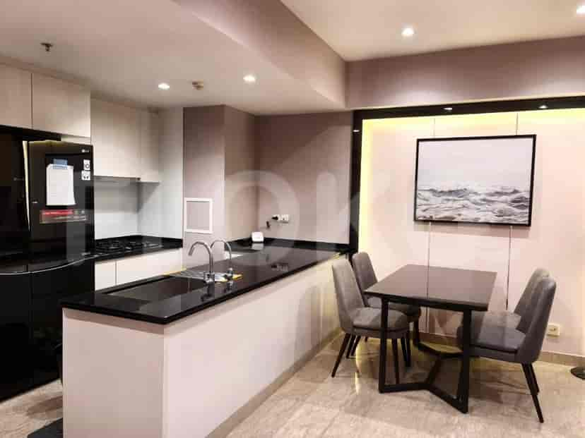 Dapur modern dengan meja hitam, lemari putih, dan area makan.
