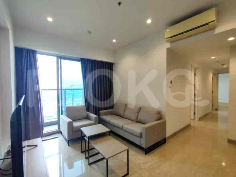 Ruang tamu modern dengan sofa abu-abu, jendela besar, dan TV yang dipasang.