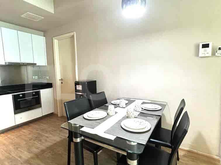 Dining area with a glass table and black chairs, and a kitchen with white cabinets.