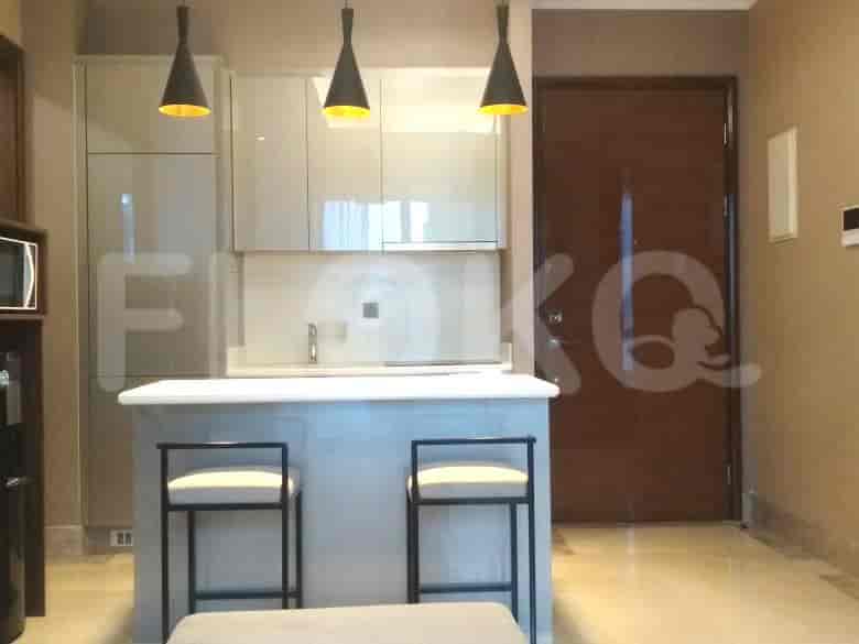 A kitchen area with a countertop, bar stools, and kitchen cabinets.