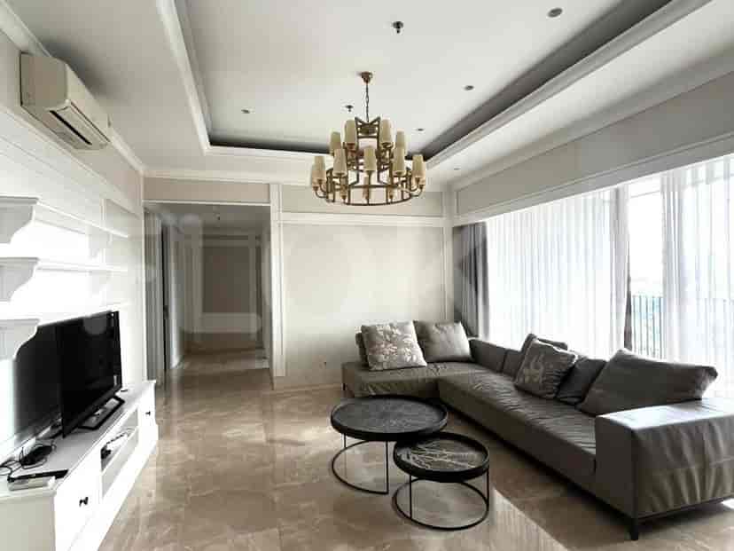 Spacious living room with grey sofa, a wall-mounted TV, and large windows with sheer curtains.