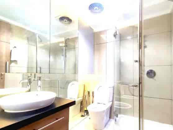 Kamar mandi modern dengan pancuran kaca dan cermin besar.