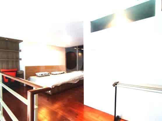 Kamar tidur loteng dengan lantai kayu keras dan tempat tidur besar.