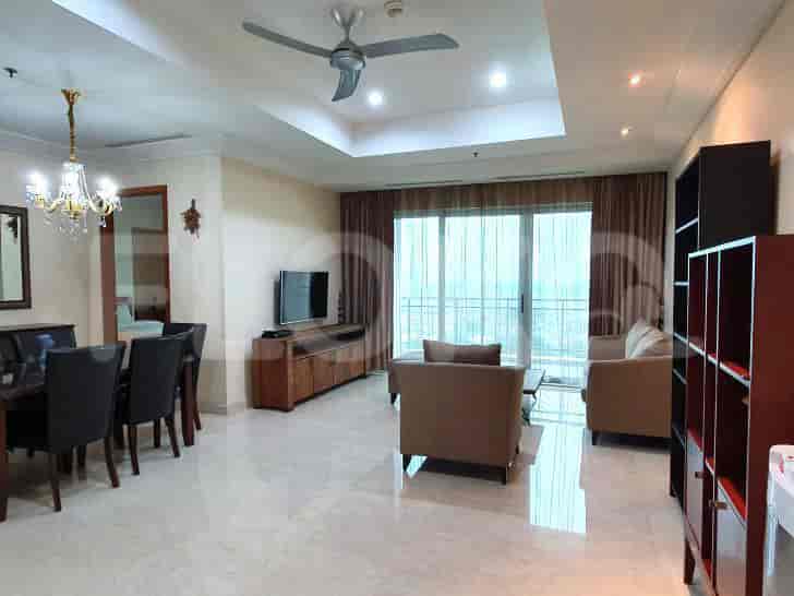 A well-lit living and dining area with a chandelier, wooden furniture, and a view of the city.