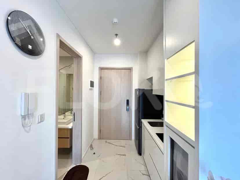Entrance hallway with a door leading to the bathroom, a kitchen, and a clock.