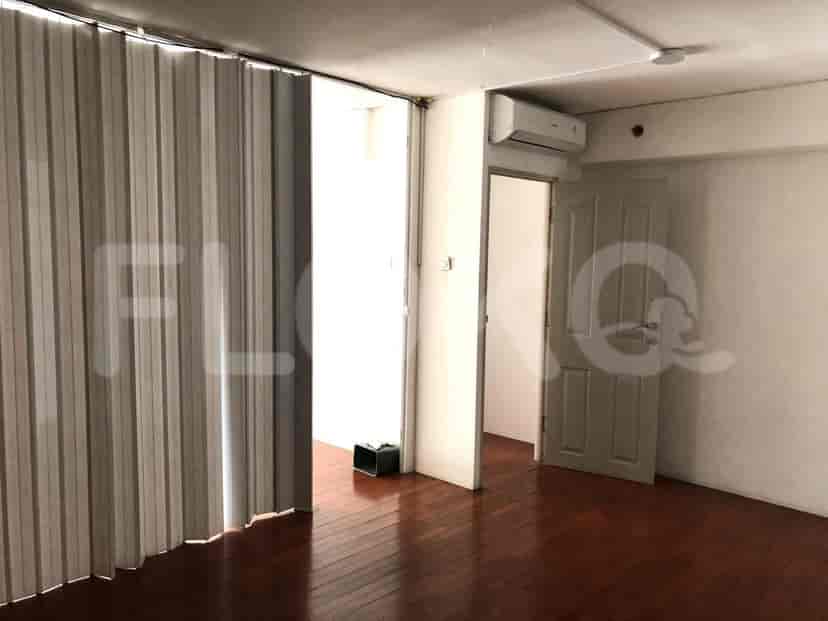 An empty room with wood flooring, a white wall, and a glimpse of an adjacent room.