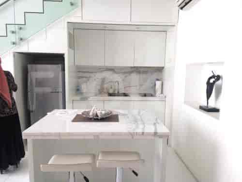 A contemporary kitchen featuring marble countertops, white cabinetry, and a central island.
