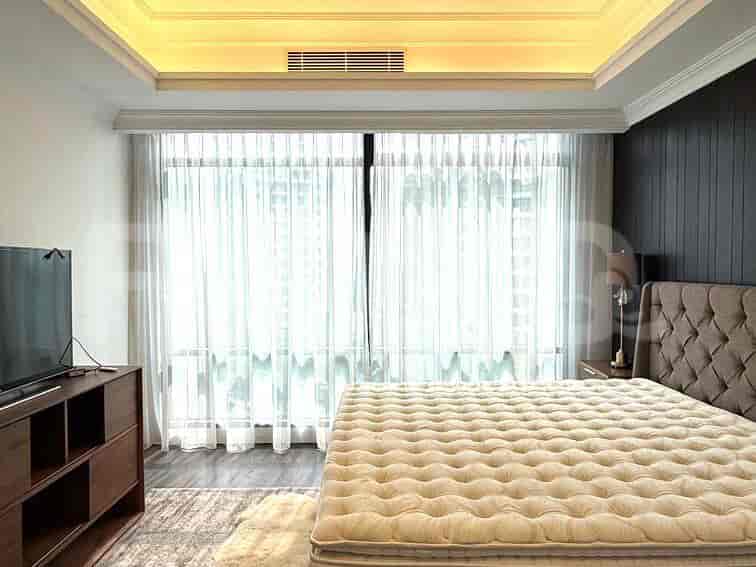 Kamar tidur yang menampilkan tempat tidur, TV, dan jendela dengan gorden tipis.