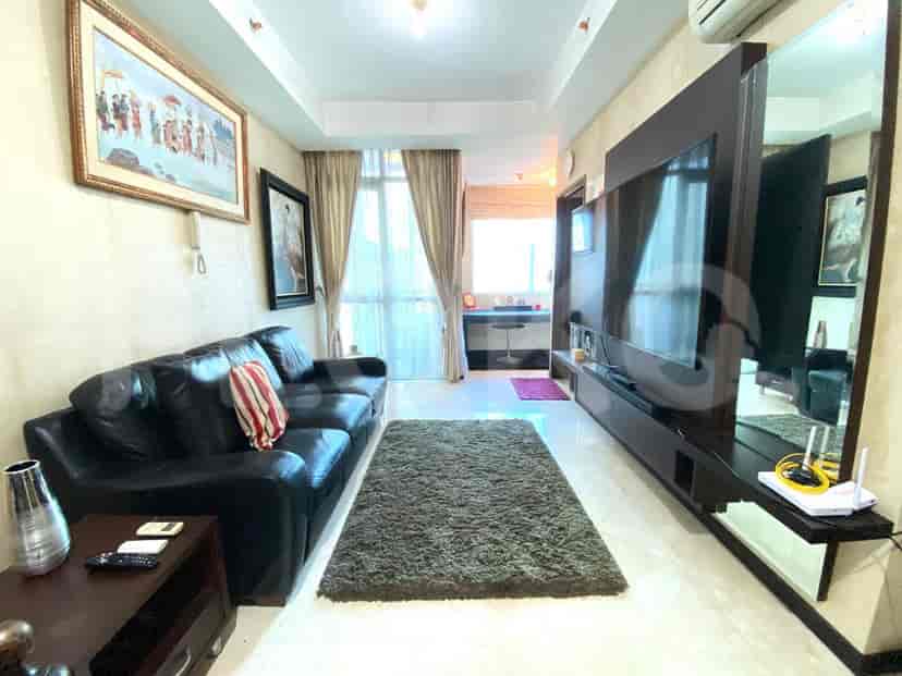 A living room with a black leather sofa, a large TV, and a view outside the window.