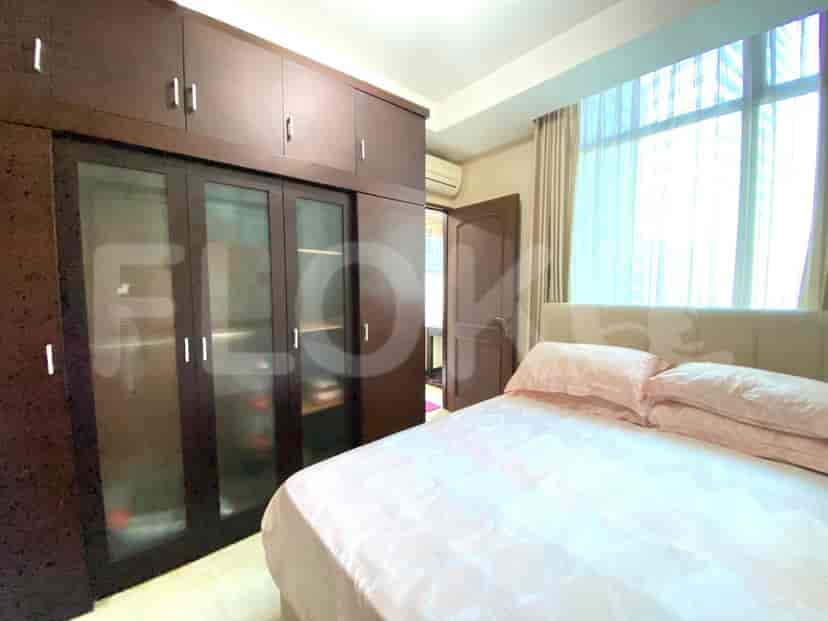 A bedroom with a bed, a wardrobe, and a window with curtains.