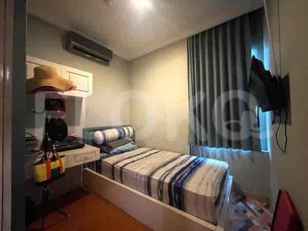 Kamar tidur kecil dengan tempat tidur tunggal, meja, dan TV yang dipasang di dinding.