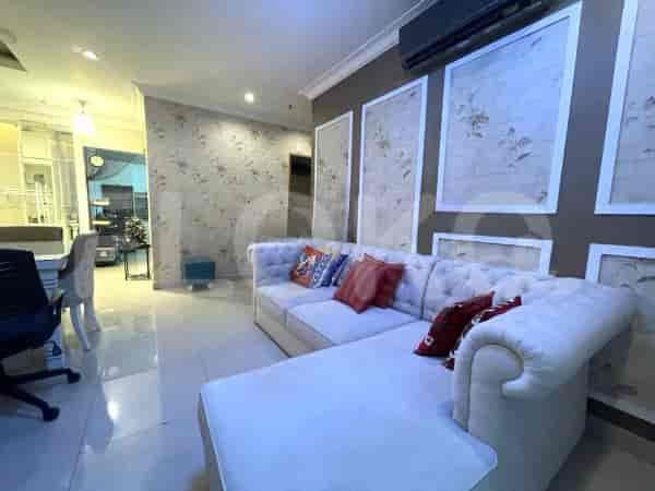 Area ruang tamu yang luas dengan sofa putih berbentuk L, panel dinding dekoratif, dan lantai berubin.