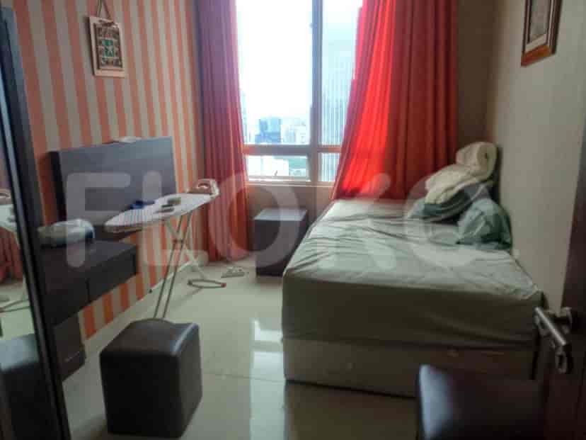 A small bedroom with a bed, mirror, and ironing board near a window.