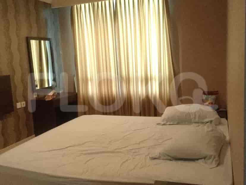 A bedroom featuring a large bed, side tables, mirror and window curtains.