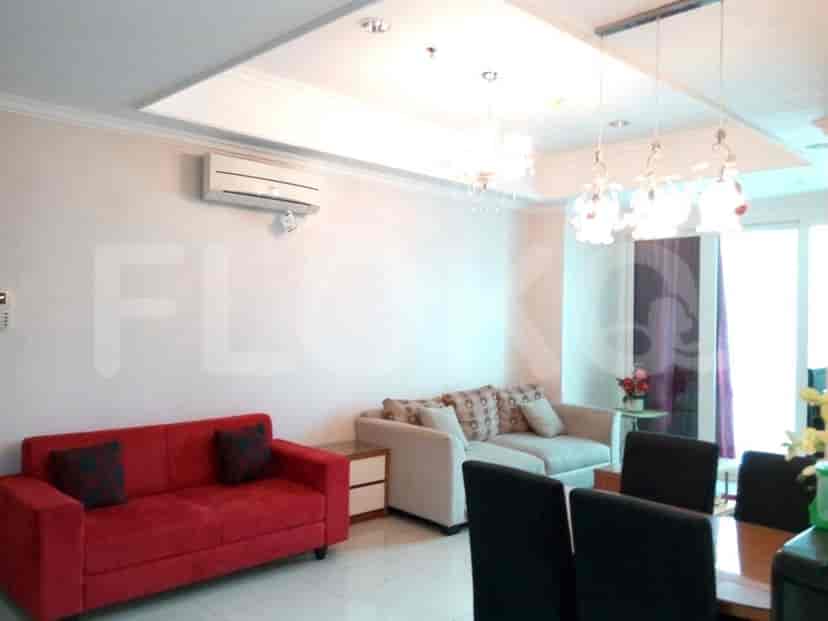 A living room with red and beige sofas, dining area, and air conditioning.