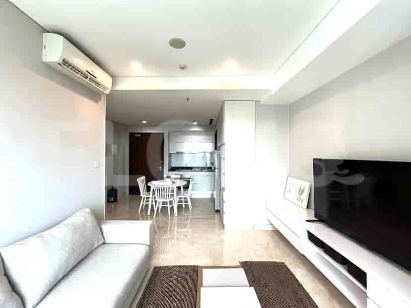 Living room featuring a grey sofa, wall-mounted TV, and dining area with a round table.