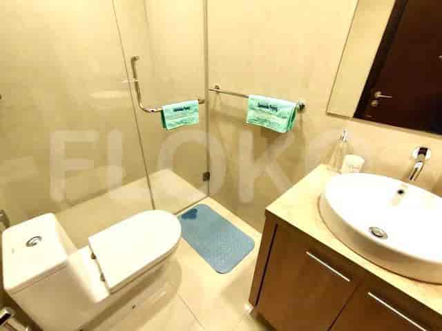 A bathroom with a toilet, sink, and glass shower enclosure.