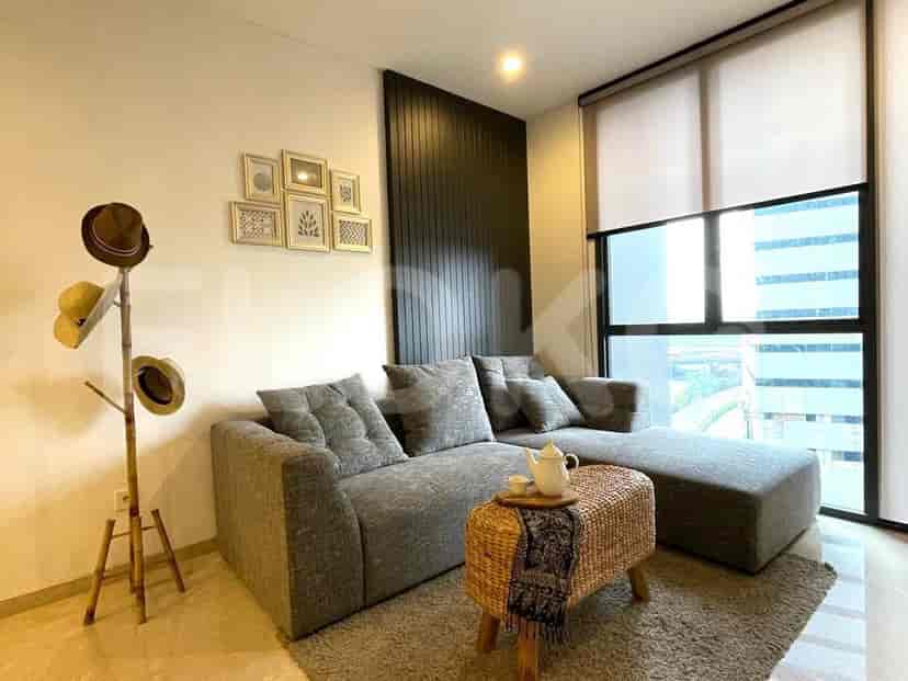 Ruang tamu dengan sofa berbentuk L abu-abu, topi hias, dan desain modern.