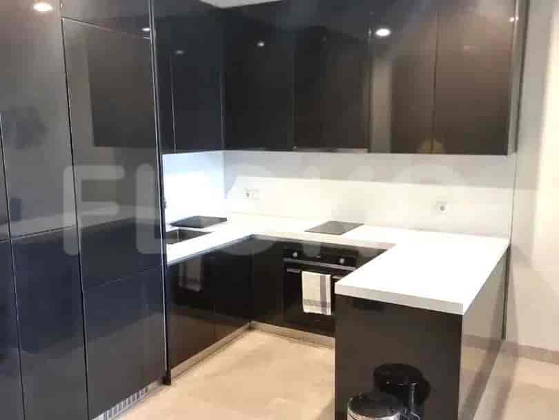 A modern kitchen with glossy black cabinets, white countertops, and built-in appliances.