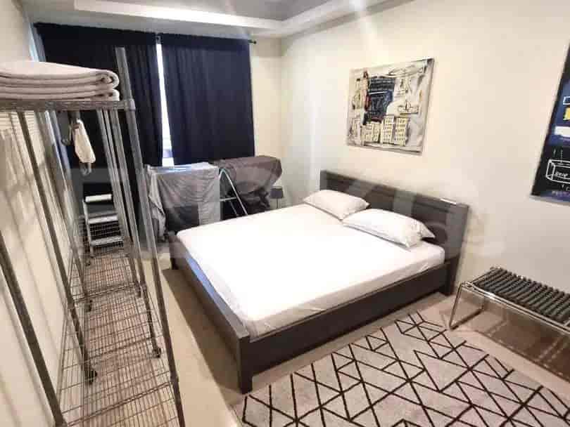 A bedroom with a bed, artwork, and a clothes rack.