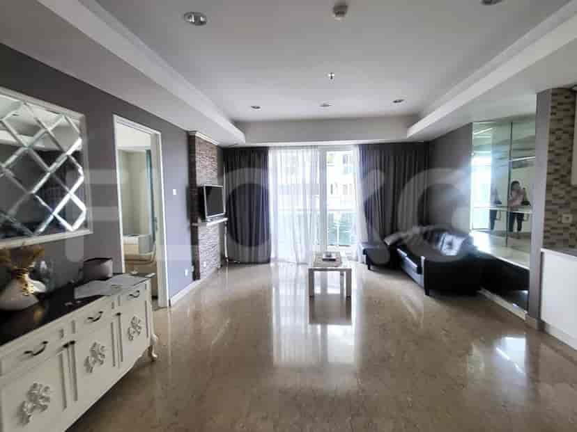 A spacious living room with marble flooring, a black sofa, and a wall-mounted TV.
