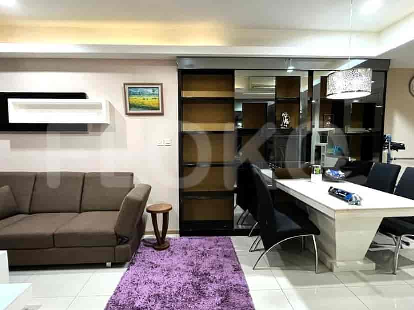 A combined living and dining area with a brown sofa, dining table, and a purple rug.