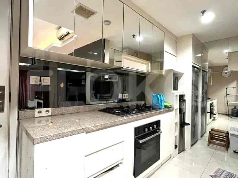 A kitchen with a mirrored backsplash, gas stove, and white cabinets.