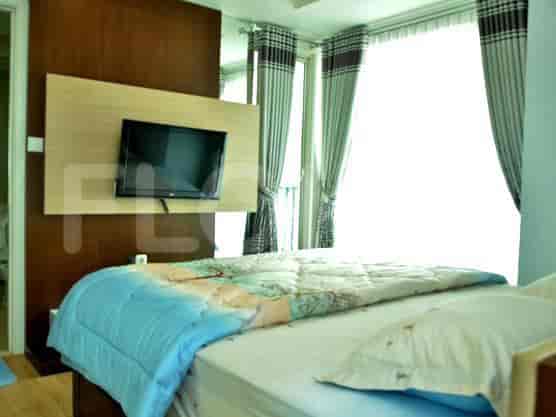 Kamar tidur modern dengan TV, tempat tidur, dan jendela besar.