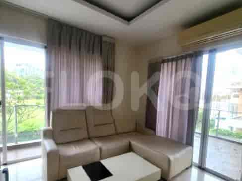 A modern living room with an L-shaped beige sofa, glass balcony, and a small coffee table.