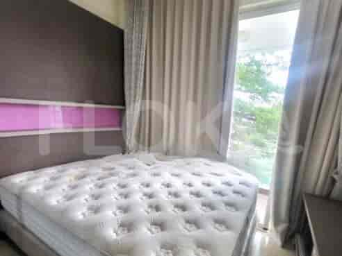 A bedroom with a bed, a large headboard, and a curtain.