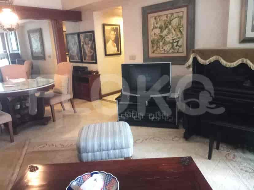 Ruang tamu dengan karya seni, piano, dan meja makan.