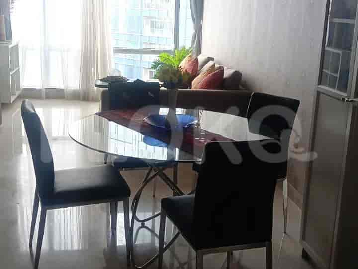 A dining area with a glass table, four black chairs, and a view of the city.
