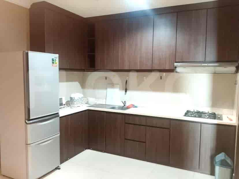 A kitchen with dark brown cabinets, a refrigerator, and a stove.