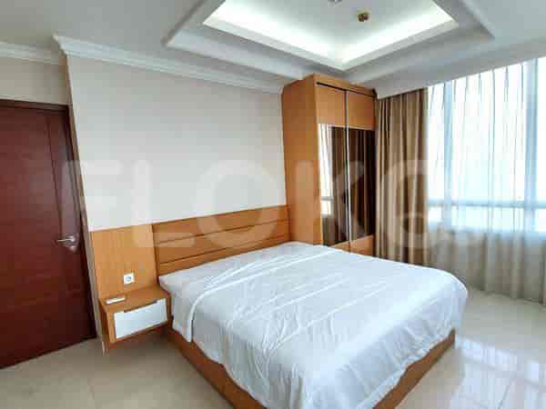 A well-lit bedroom with a large bed, wooden headboard, and closet.