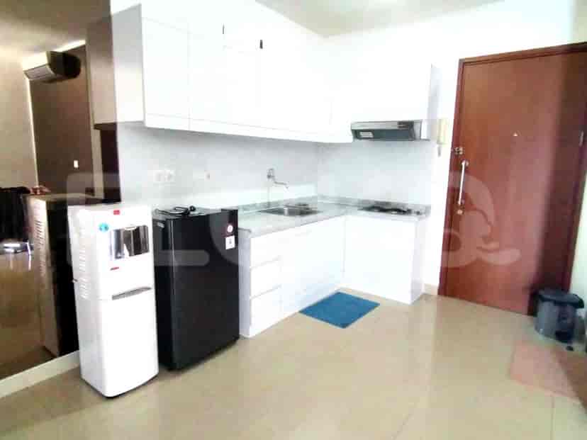 A kitchen with white cabinets, a refrigerator, and a water dispenser.