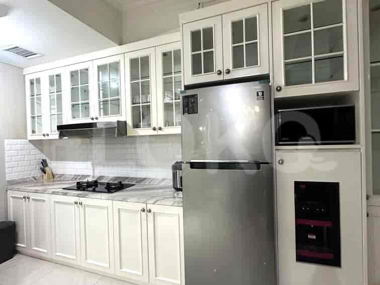 Dapur yang dilengkapi dengan lemari putih, kulkas baja tahan karat, dan meja marmer.