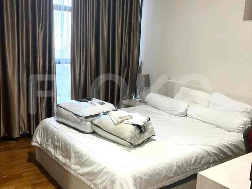 Kamar tidur dengan tempat tidur besar, sprei putih, dan jendela dengan gorden cokelat.