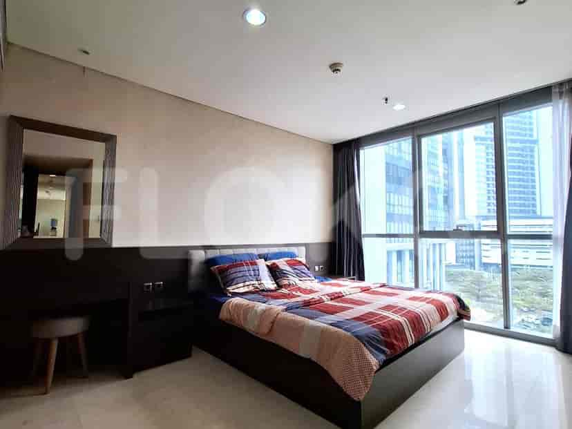 A bedroom with a large bed, a desk, and a window with city views.
