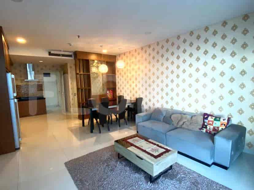 Ruang tamu dengan sofa biru, area makan, dan pintu masuk dapur.
