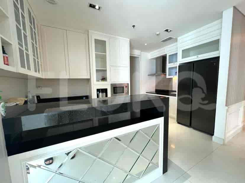 Dapur modern dengan lemari putih, meja hitam, dan pulau berubin cermin.