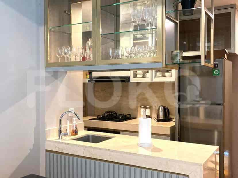 A modern kitchen with a marble countertop, overhead cabinets, and stainless steel appliances.