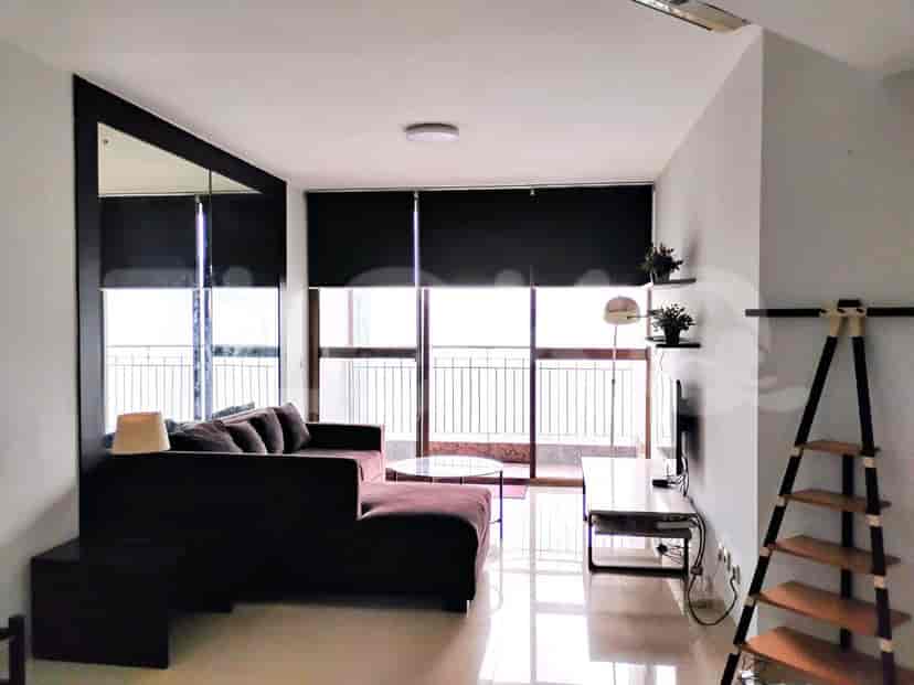 Modern living room with a dark brown L-shaped sofa and large windows overlooking the city.
